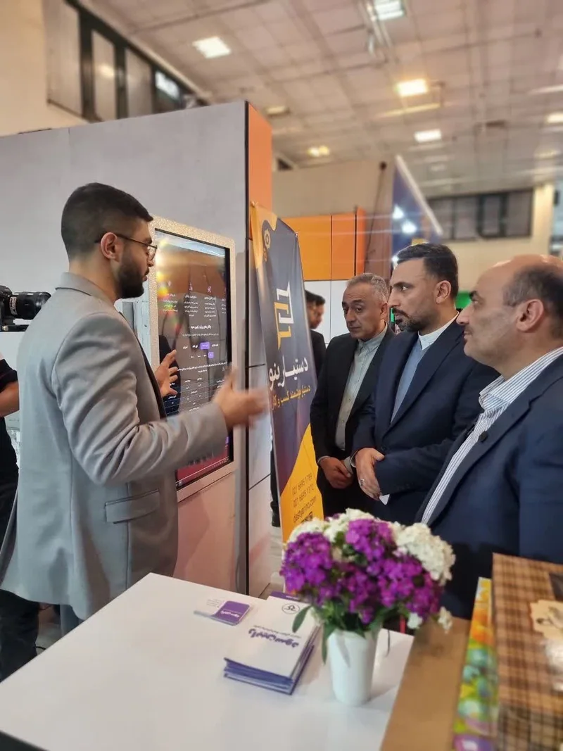 کارشناس رابینسود ابزارهای پلتفرم را روی نمایشگر غرفه به بازدیدکنندگان نمایشگاه تراکنش ایران نشان میدهد