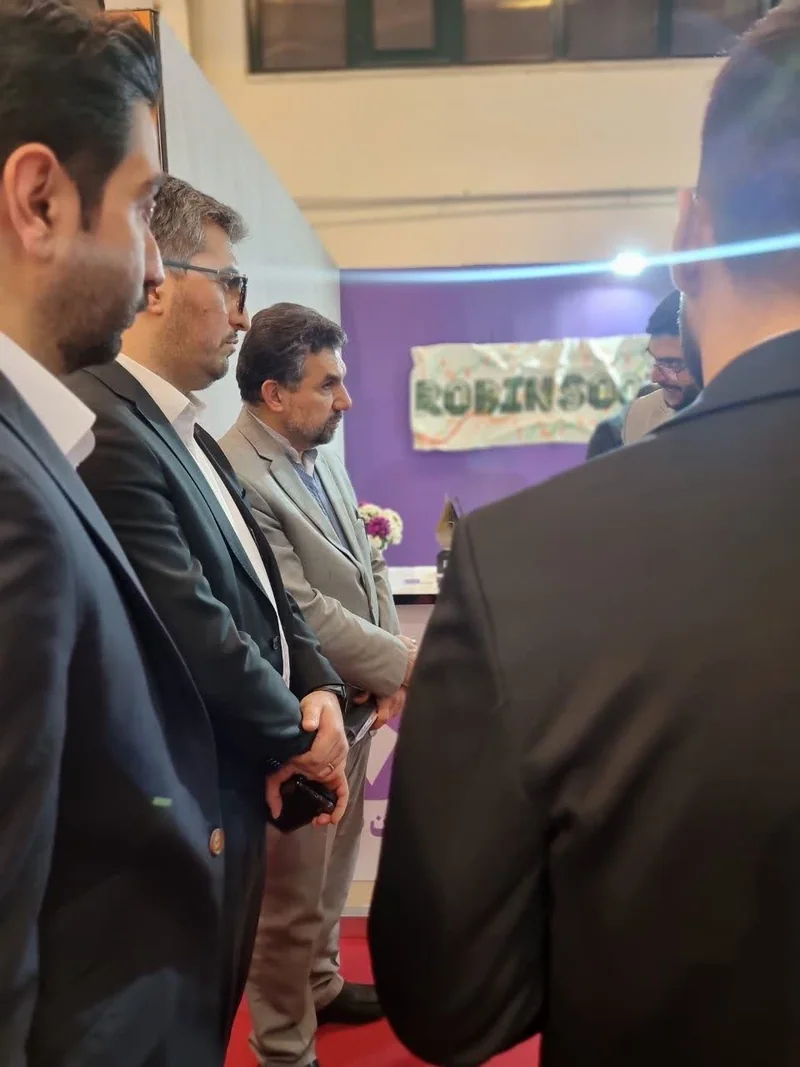 گفت‌وگوی مدیران و مهمانان کت‌وشلواری کنار تابلوی رابین‌سود در غرفه نمایشگاه تراکنش ایران