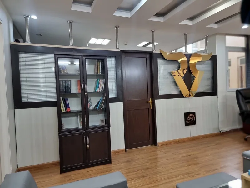 نشان طلایی رابین‌سود روی دیوار دفتر تهران کنار کمد کتاب و در ورودی